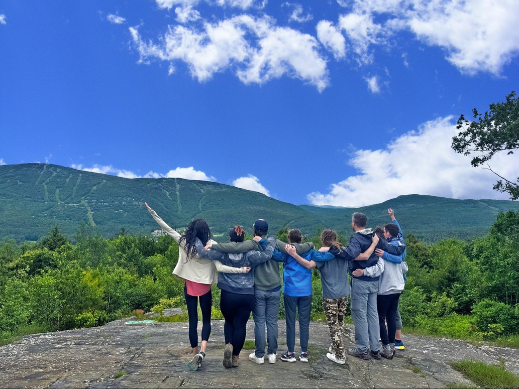 A group standing together overlooking the mountains, from Divided Sky’s supplied materials